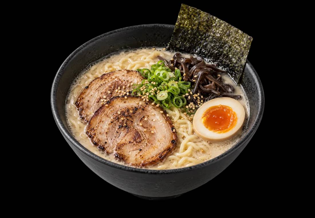A black bowl of tonkotsu ramen with torched chashu, a jammy egg, wood ear, scallion and nori